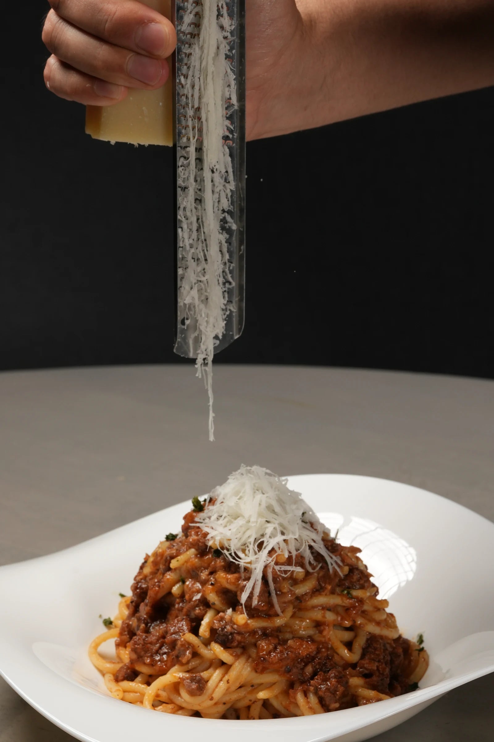 肉のラグーをパスタと合わせ、チーズを添えた盛り付け例